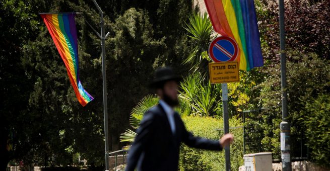 Ein ultra-orthodoxer Jude läuft eine Straße entlang, die für die Jerusalemer Gay-Pride-Parade mit Regenbogenfahnen dekoriert wurde.